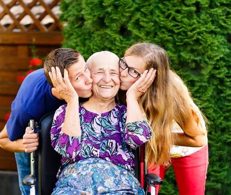 32727955 contented grandmother being loved and kissed by beautiful grandchildren 